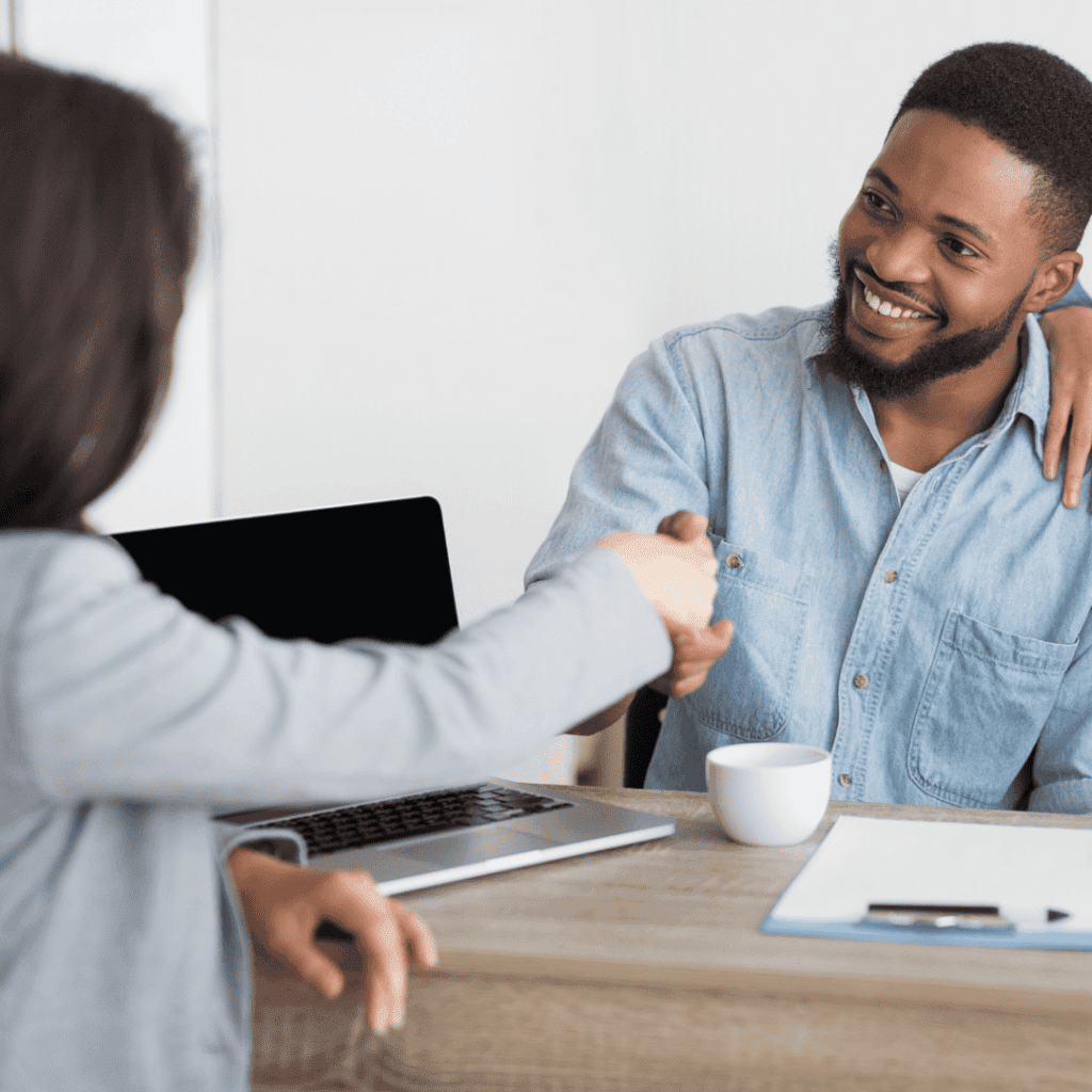 Smiling afro spouses handshaking with insurance broker in office